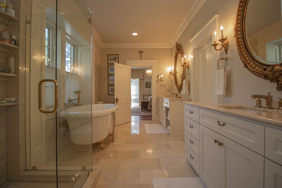 Traditional bath with a clawfoot tub, gilded mirror and glass shower