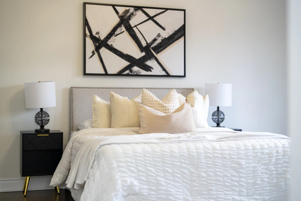 Bedroom staged with bold black-and-white art, white bedding and matching lamps