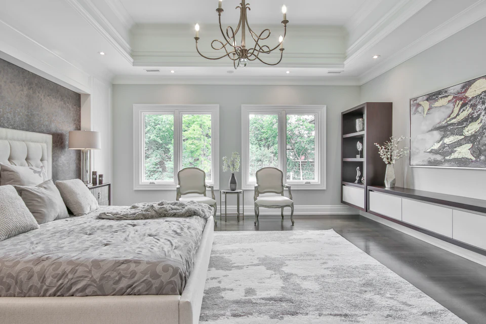 Luxury bedroom with a chandelier, tufted headboard and sitting area by the windows