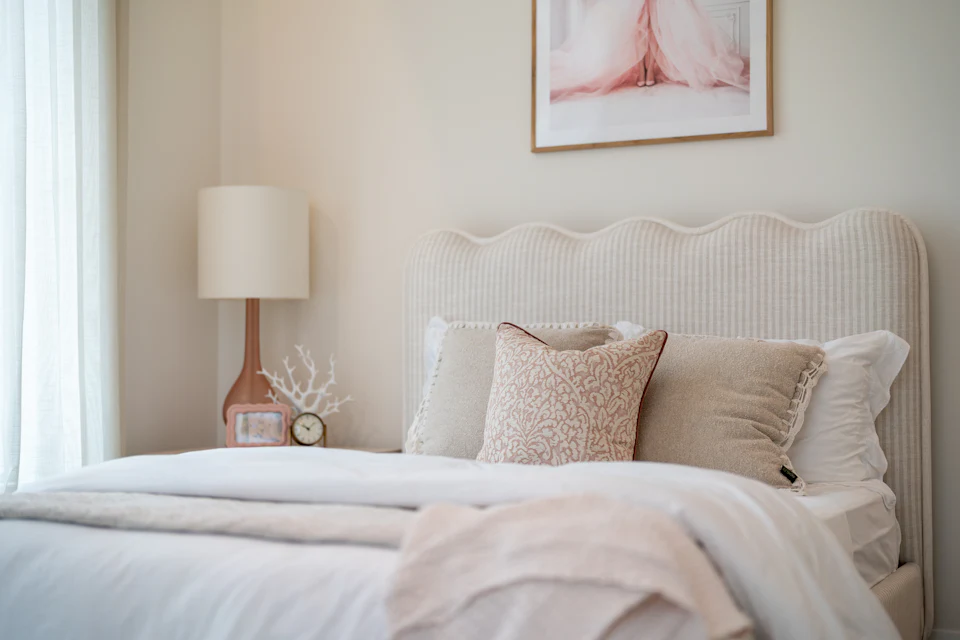 Guest bedroom styled with a scalloped headboard, ceramic lamp and soft blush accents