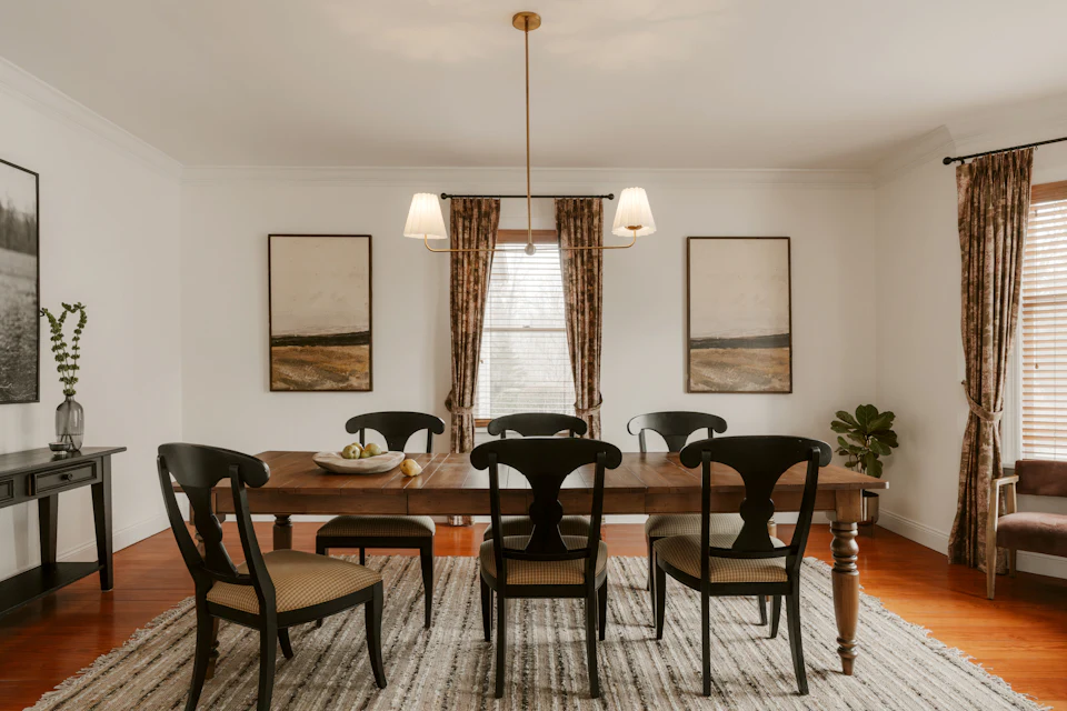 Traditional dining room with a farmhouse table, black chairs and framed art