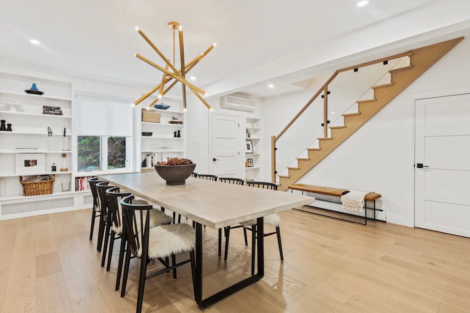 Long dining table with Windsor chairs under a brass chandelier