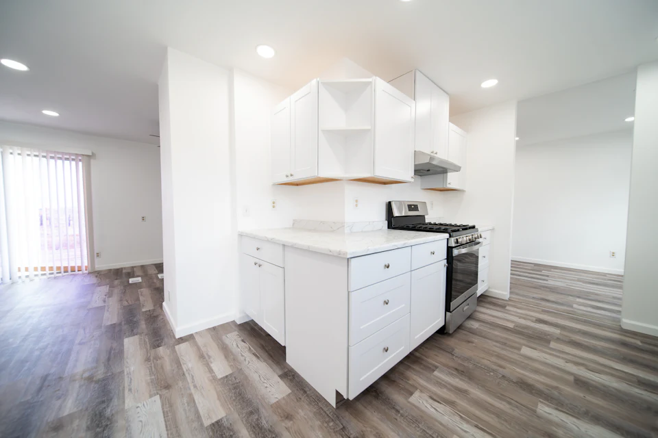 Before staging — Vacant kitchen with white cabinets, bare counters and open floor