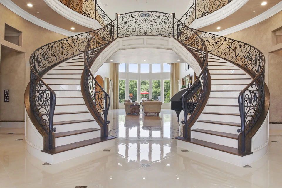 Grand foyer with a double curved staircase and polished marble floors