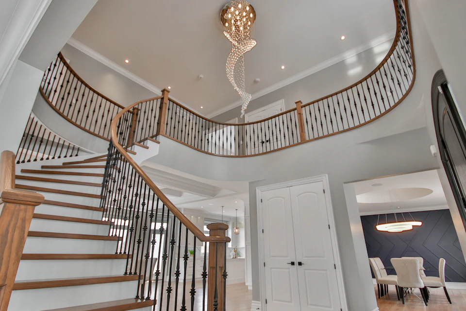 Bright two-story foyer with a curved staircase and crystal chandelier