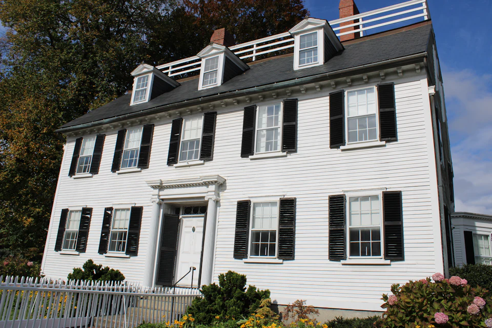 Traditional white colonial home with black shutters and dormer windows