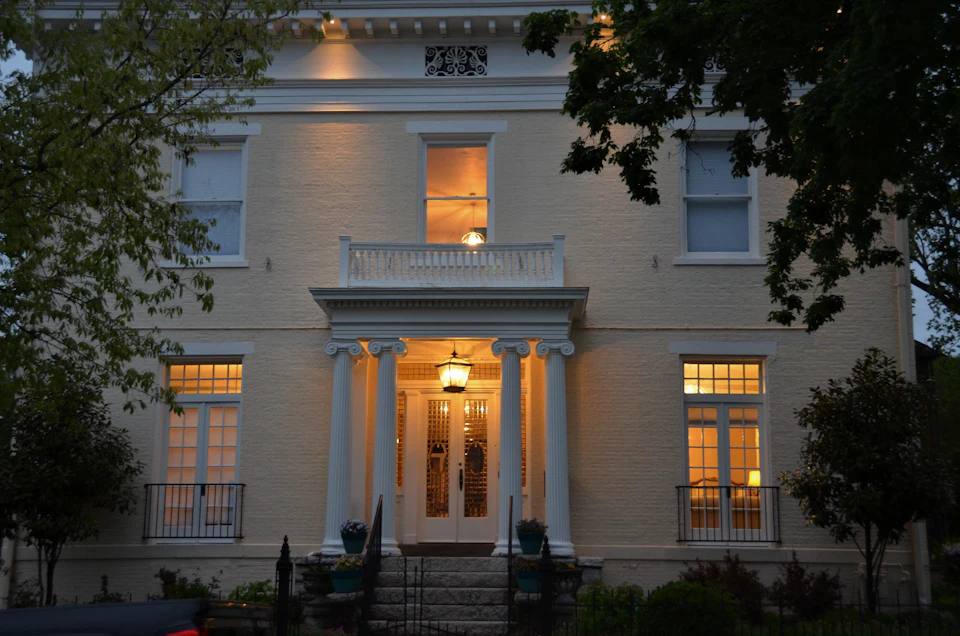 Classic white Greek Revival home with columns, softly lit at twilight