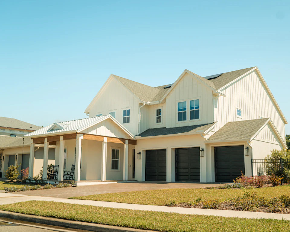 Newly built white farmhouse-style home with a front porch and three-car garage