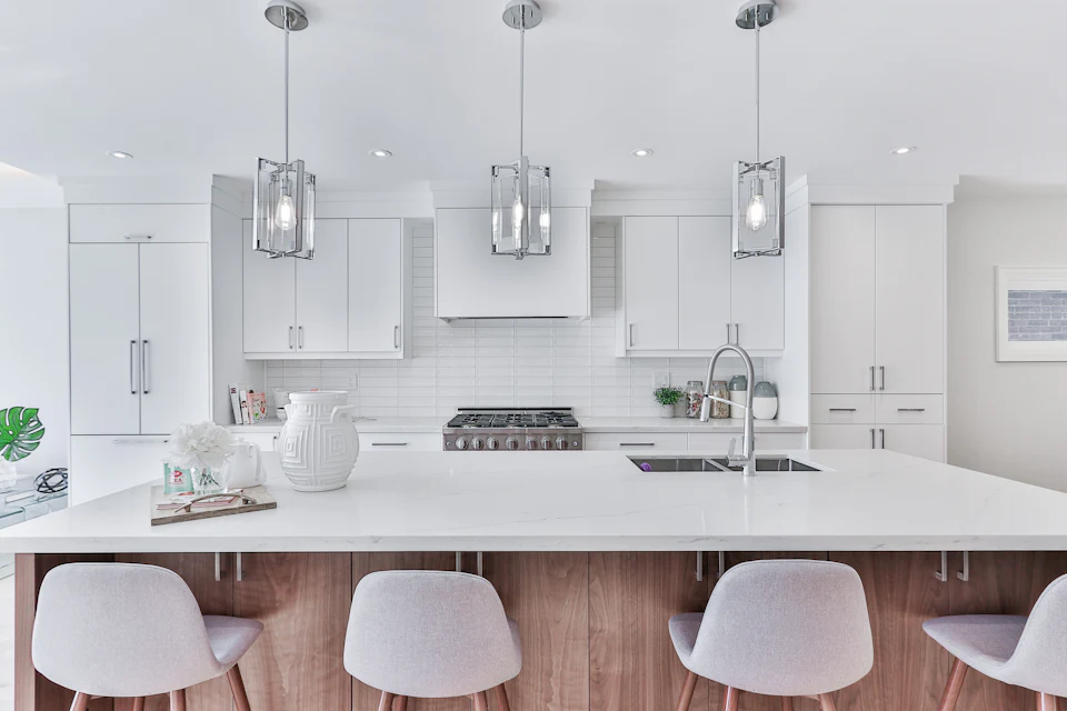 White kitchen with lantern pendants, quartz island and white stools