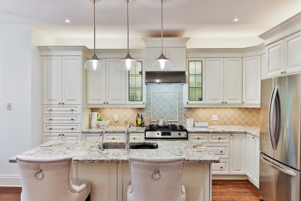 Traditional kitchen with cream cabinetry, granite island and glass pendants