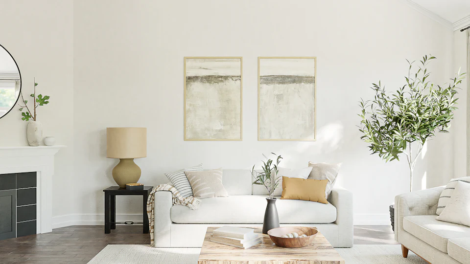 Airy staged living room with a white sofa, abstract art, linen lamp and olive tree