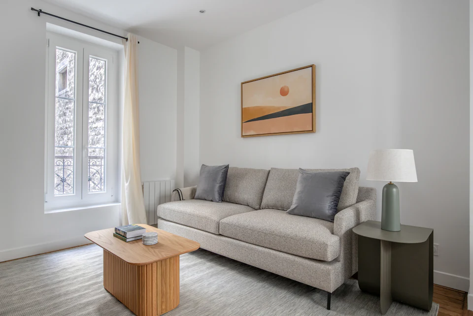 Simply staged condominium living room with a gray sofa and warm abstract art