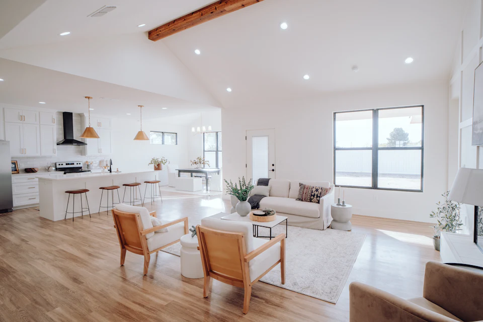 Open-concept great room staged with leather chairs flowing into a white kitchen