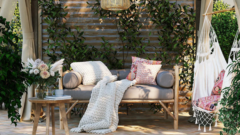 Cozy covered porch with a cushioned daybed, knit throw and hanging chair