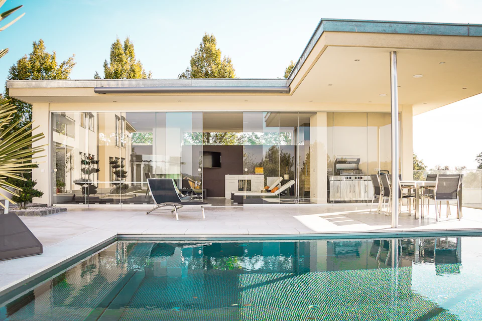 Covered outdoor living area beside a pool with lounge seating