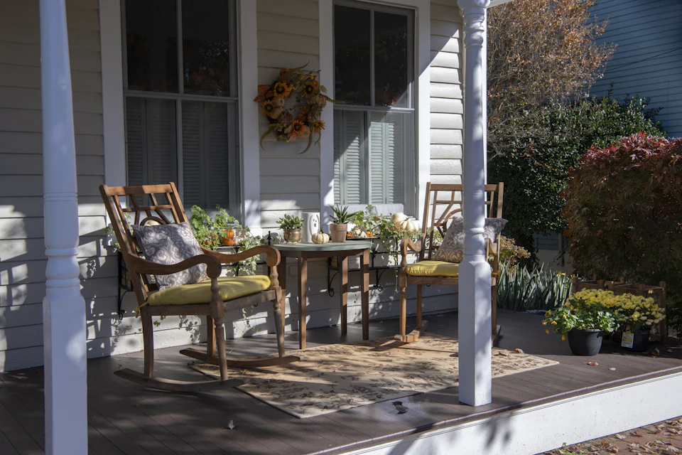 Inviting front porch styled with cushioned chairs, potted plants and a seasonal wreath